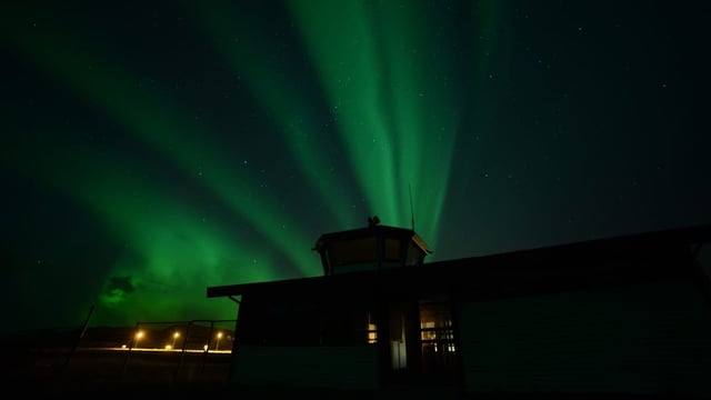 Grüne Strahlen am Sternenhimmel, Tower-Gebäude im Dunkeln.