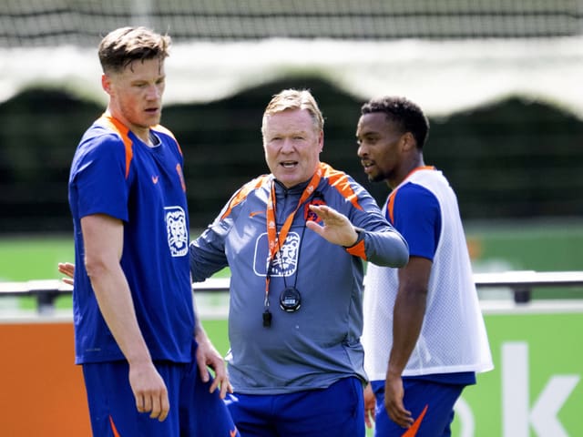 Drei Fussballspieler in Trainingskleidung auf dem Spielfeld.