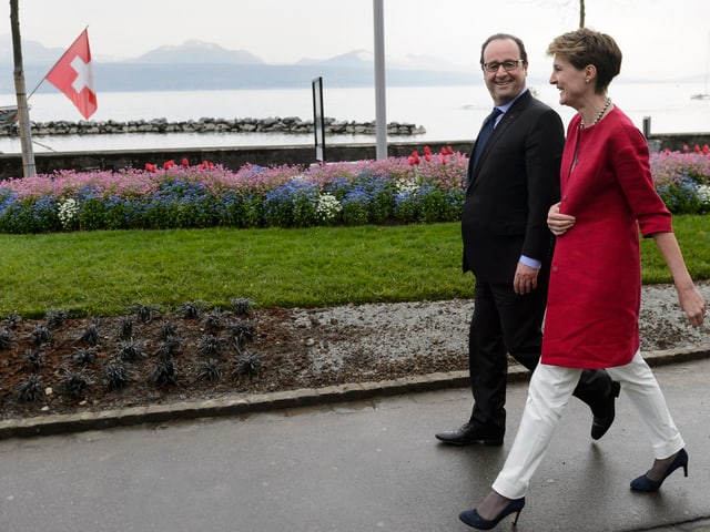 Sommaruga und Hollande entlang eines Ufers schreitend.