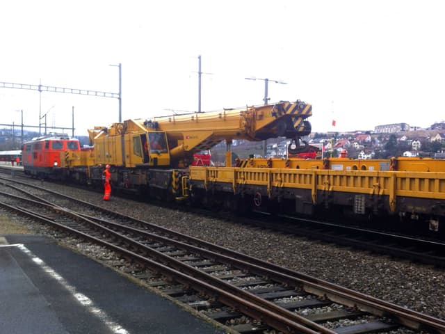 Der Kran hebt die Lokomotive auf Hilfsräder, damit sie weggezogen werden kann.