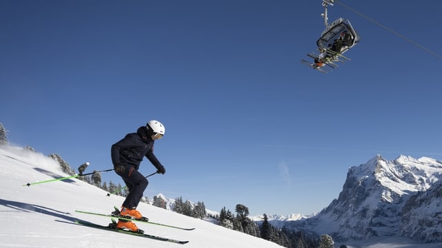 Ein Skifahrer auf der Piste und weitere Skifahrer in der Gondel