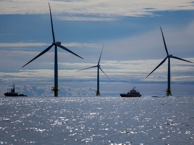 Offshore-Windkraftanlagen und Boote auf dem Meer.