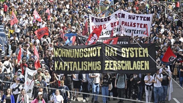 Menschenmassen bei einem Protest mit Bannern und Schildern.