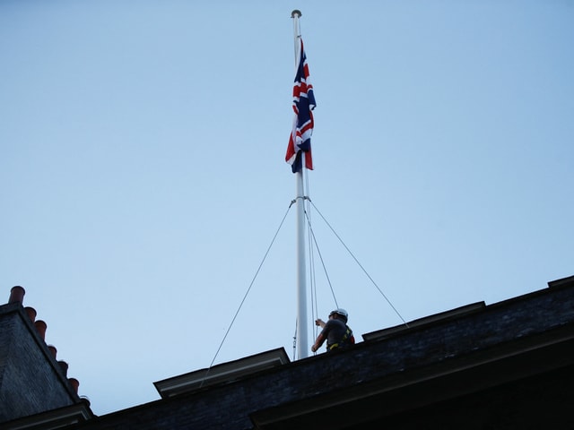 A man lowers the flag at Buckingham Palace