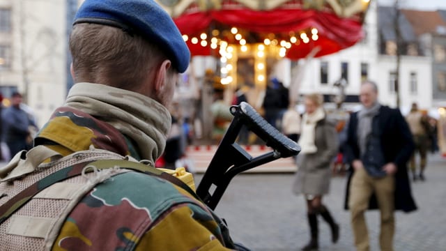 Symbolbild: Bewaffneter Soldat vor einem beleuchteten Karussell.