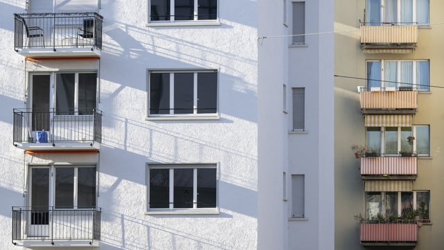 Ein weisser Wohnblock mit Balkons steht neben einem gelben Wohnblock mit Balkons