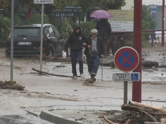 Menschen waten durch überflutete Strasse in starkem Regen.