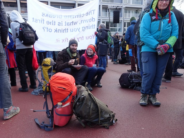 Demonstranten sitzen am Boden und essen. 