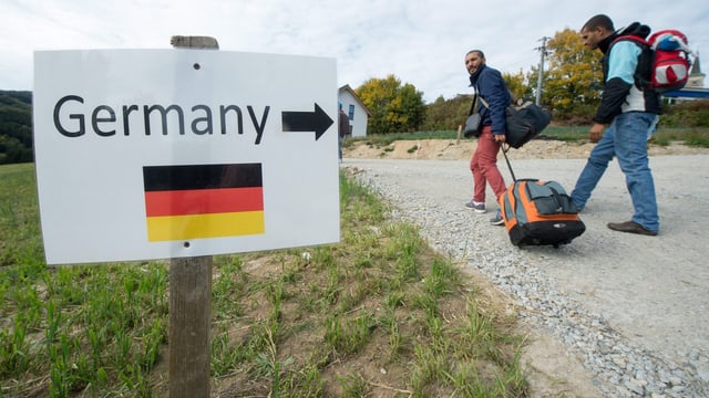 Zwei Flüchtlinge passieren ien Schild mit der Aufschrift «Germany».