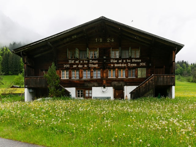 Ein altes Holzhaus mit einem Dach, das aus zwei schrägen Flächen besteht.