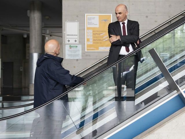 Two men on an escalator.