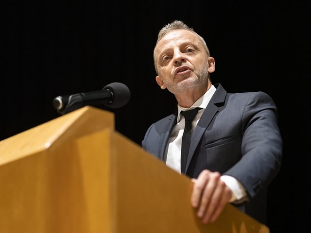 Hans-Ueli Vogt spricht auf einem Podium.