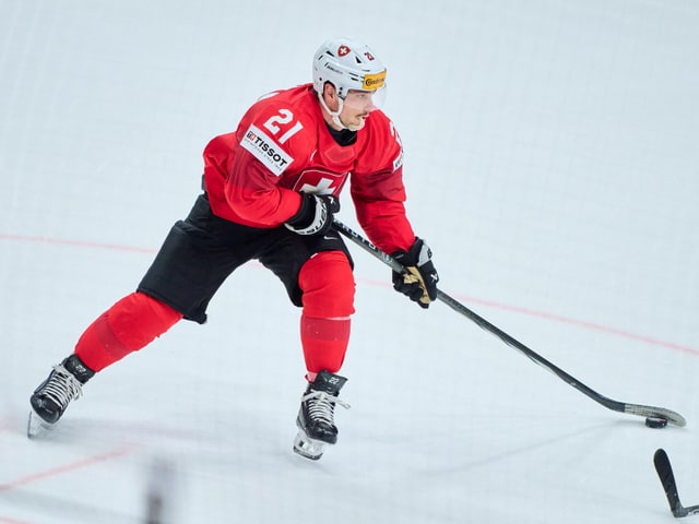 Eishockeyspieler in roter Ausrüstung auf dem Eis beim Spielen.