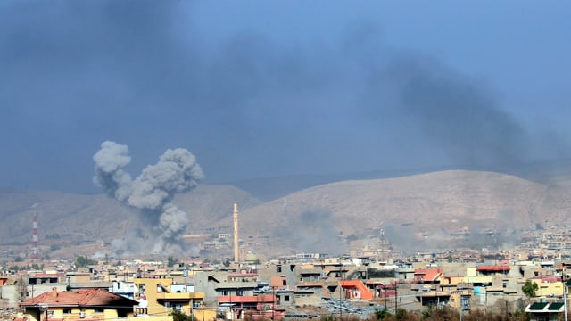 Explosionswolken über Häusern einer Ortschaft.