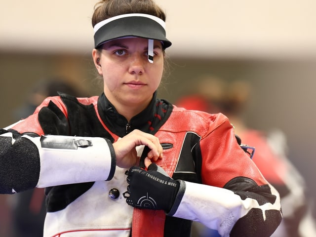 Frau beim Sportschiessen in Schutzkleidung.