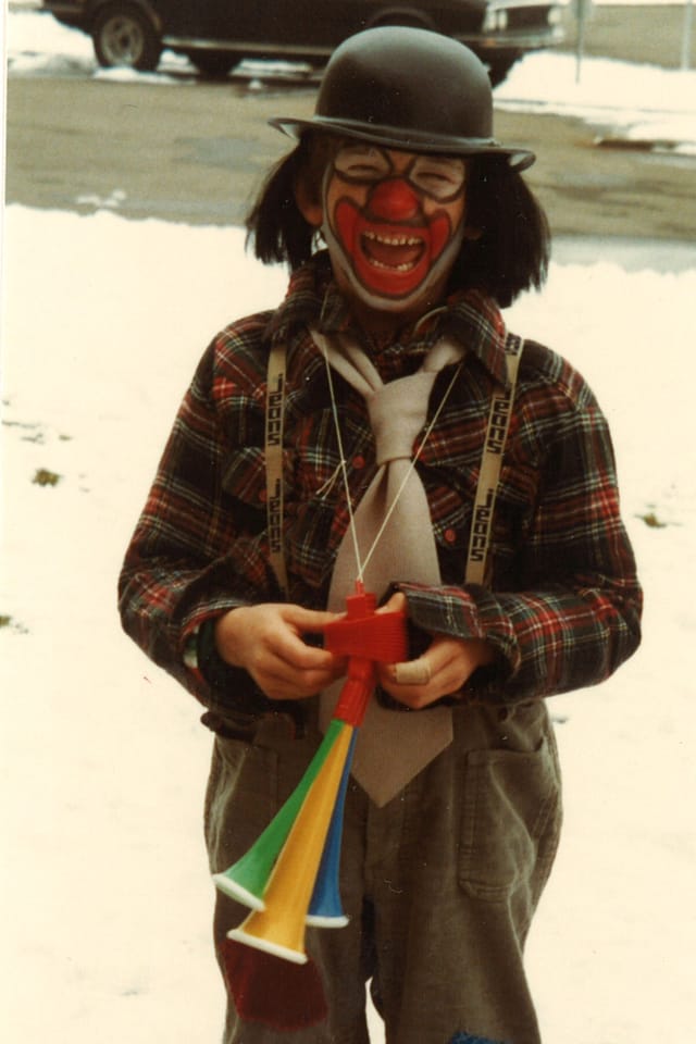 Ein Bub, der als Clown geschminkt und verkleidet ist.