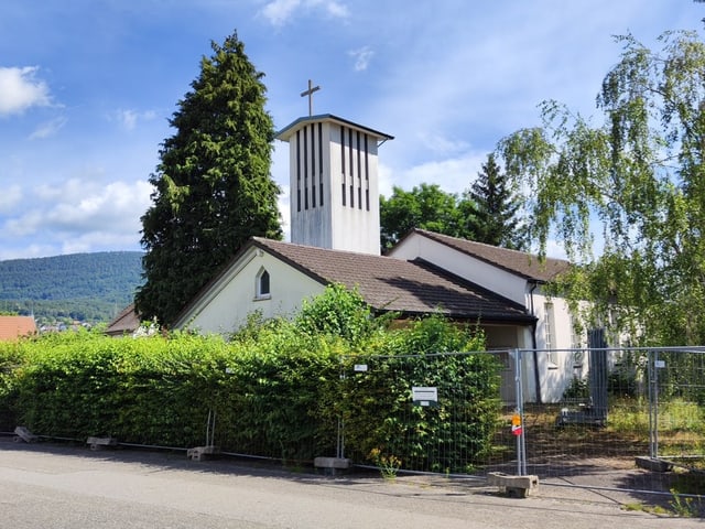 Kirche hinter einer Hecke, sonniger Tag.