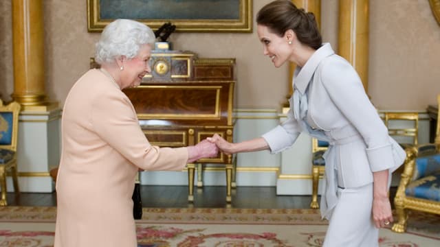 Die Queen und Angelina Jolie reichen sich die Hände. 