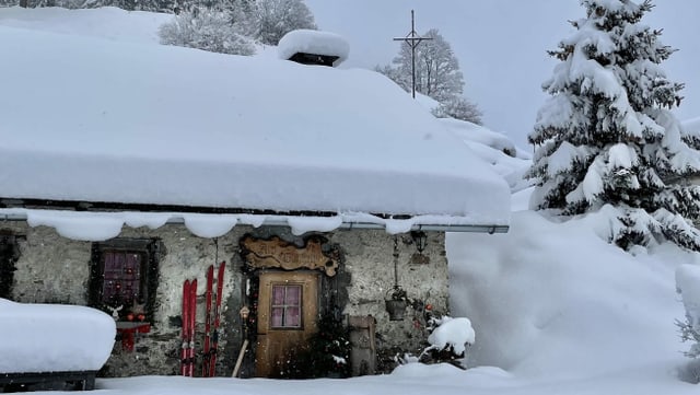 Mountain shelter with lots of snow on the roof.