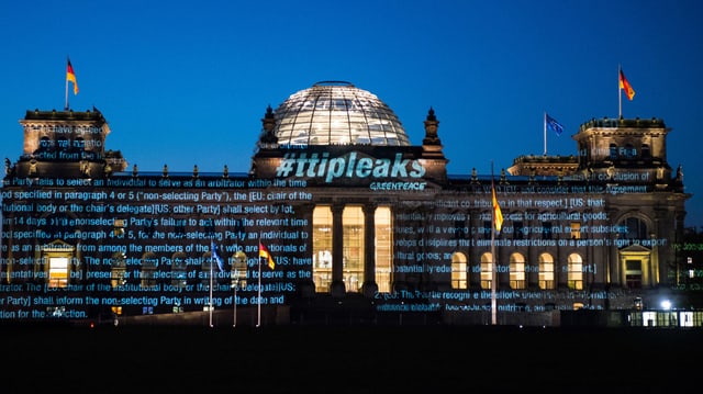 Reichstagsgebäude in Berlin am frühen Morgen – mit darauf projizierten Schriftzügen. 