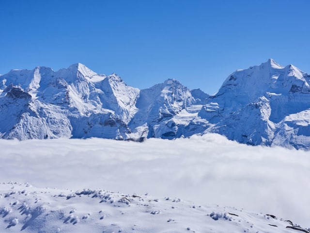 Schneebedeckte Berge über Wolken.