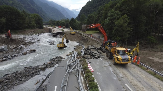 Strassenbauarbeiten an einer durch eine Überschwemmung beschädigten Strasse neben einem Fluss.