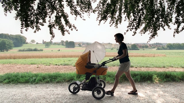 Eine Mutter geht mit ihrem Baby im Kinderwagen auf dem Land spazieren.