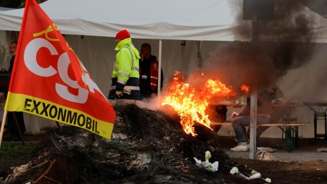 CGT-Flagge, ein Mann in Leuchtweste und ein Feuer. Die Französinnen und Franzosen streiken seit Tagen.