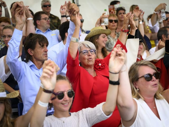 Baume-Schneider und ihr Mann halten sich an den Händen und singen mit anderen Menschen gemeinsam