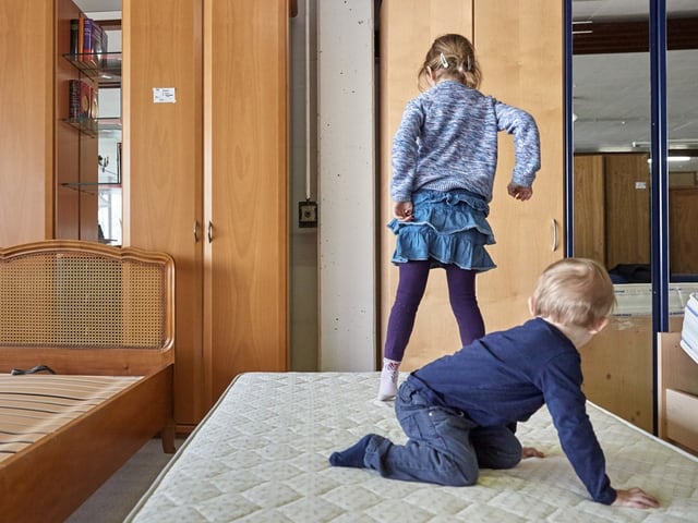 Kinder spielen auf einer Matratze im Schlafzimmer.