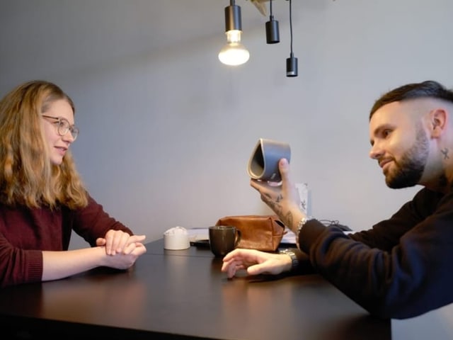 Livio und Rebecca Weiss sitzen am Tisch. Livio hält Prototyp in der Hand und betrachtet ihn interessiert.