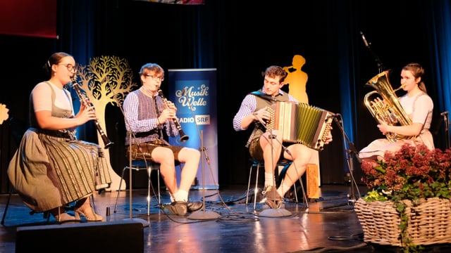 Katharina Egger, Gregor Abler, Simon Holzer und Katharina Rinner sitzen mit ihren Instrumenten auf der Bühne. 