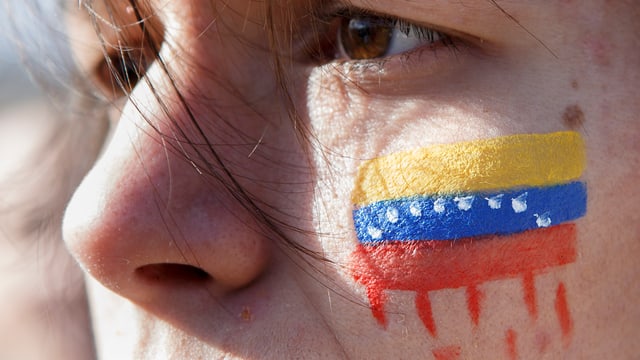 Eine Person mit einer Venezuela-Flagge auf der Wange.