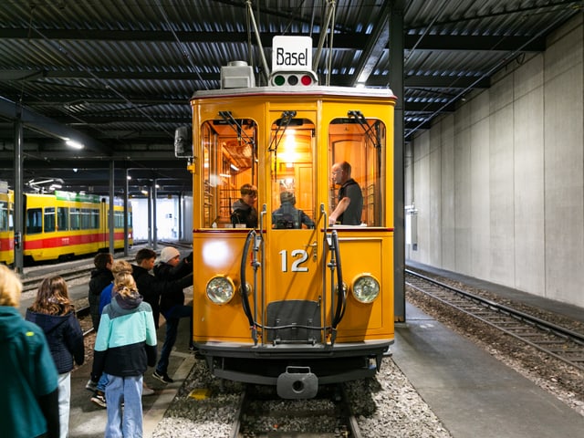 Einige Kinder laufen zu einem gelben Tram-Oldtimer.