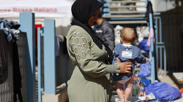 Eine Frau spielt mit einem Baby  im Erstaufnamelager auf der Insel Lampedusa.