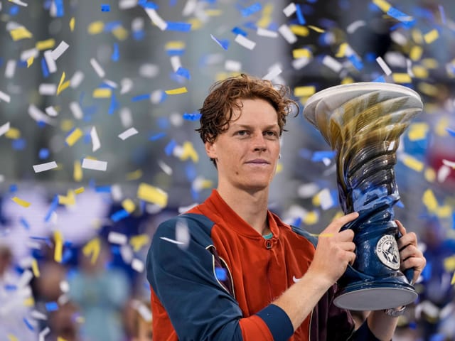 Tennisspieler mit Pokal und Konfetti im Hintergrund.