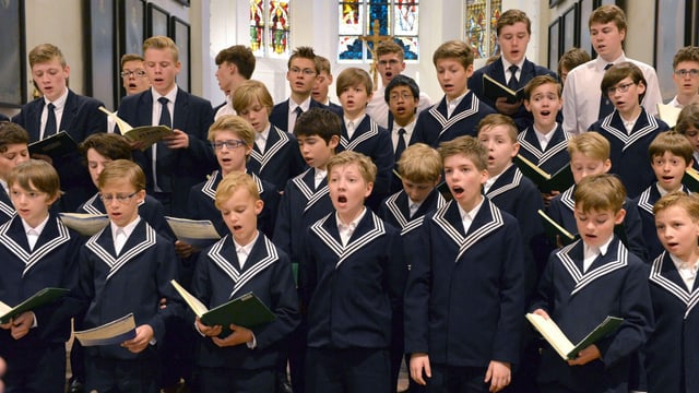 many young people in uniform singing