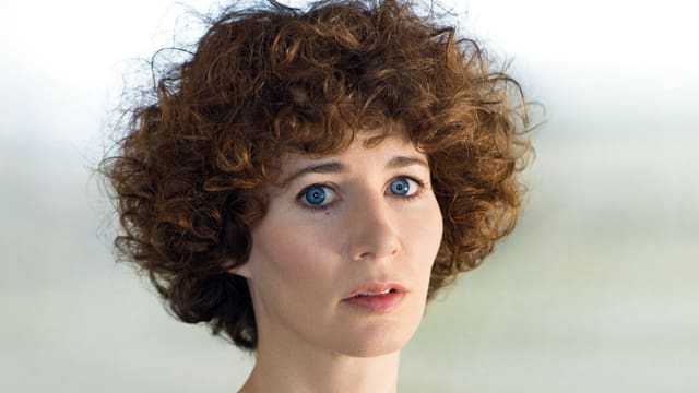 Miranda July hat lockiges braunes Haar und blaue Augen.