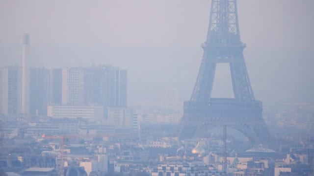 Der Eiffelturm ist von einem Dunst aus kleinen Partikeln umgeben, der über der Skyline von Paris hängt.