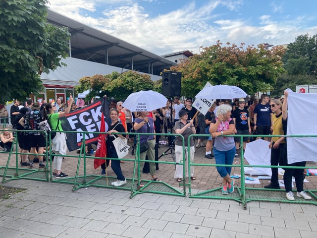 Menschenmenge bei einer Demonstration mit Schildern und Bannern.