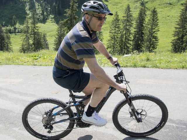 Guy Parmelin in shorts on an electric bike.