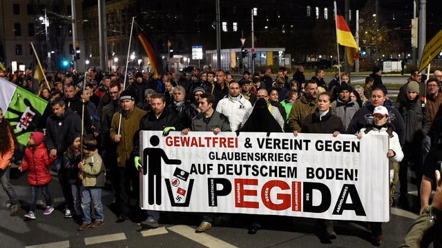 Pegidademonstration in Dresden; viele Menschen um ein Transparent mit Pegida-Schriftzug.