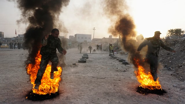 Zwei irakische Soldaten im Training rennen nebeneinander durch ein Feuer.