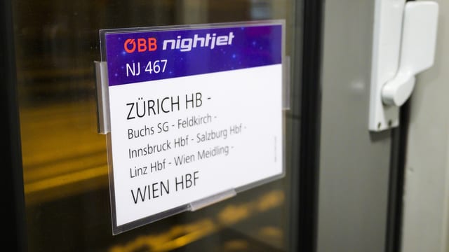 Ein Nachtzug steht an einem Bahnhof. 