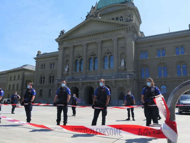 Absperrband und Polizisten mit Mundschutz vorm dem Bundeshaus. 