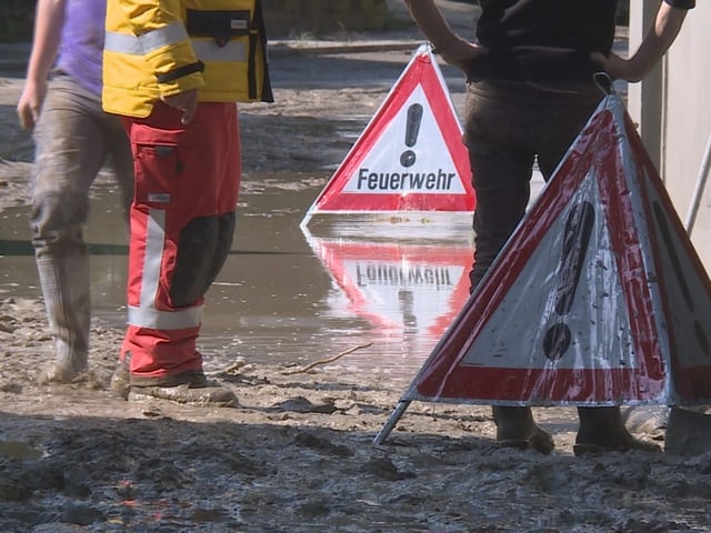 Feuerwehrschilder im Schlamm mit Einsatzkräften.