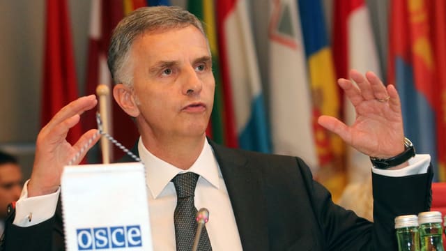 Burkhalter spricht bei seiner Antrittsrede bei der OSZE in Wien Mitte Januar in ein Mikrofon, hinter ihm sind diverse Landesflaggen erkennbar.