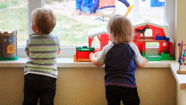 Zwei Kinder schauen aus dem Fenster