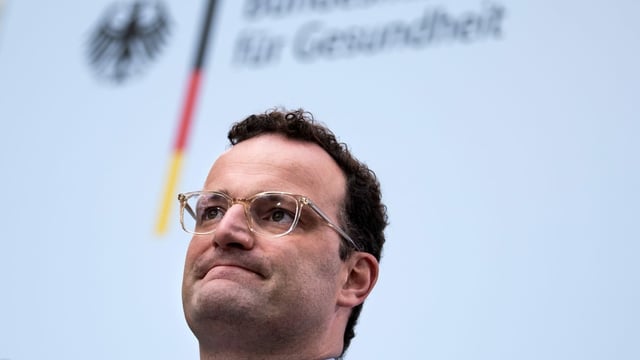 Jens Spahn at a press conference with the logo of the Ministry of Health in the background.