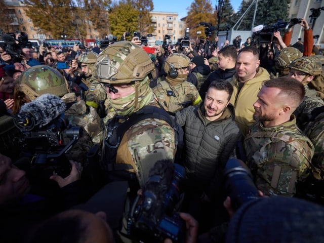 Selenski steht zwischen mehreren Soldaten innerhalb einer grossen Menschentraube.